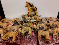 Fifteen tan Douglas plush horses, each individually wrapped in clear plastic bags, arranged with one horse on top outside packaging showing the item.