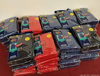 View of seventeen unopened Fruit of the Loom value packs with assorted color sleeveless T-shirts stacked in rows.