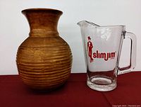 Wooden vase and Slim Jim glass pitcher side by side on red surface
