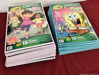 Stack of Dora the Explorer Crayola Giant Coloring Pages next to SpongeBob SquarePants Crayola Giant Coloring Pages from the lot