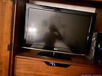 Photo of LG 42 inch flat screen TV powered off in wooden furniture setup.