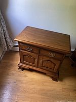 Front view of a wooden night stand with two drawers and two cabinet doors, showing polished finish and brass handles.