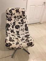 Photo of black and white fabric swivel chair with floral pattern and metal 4-legged swivel base