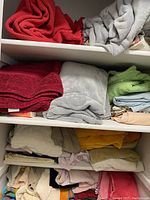 Shelves filled with an assortment of folded towels and linens in various colors such as red, gray, green, blue, beige, and mustard yellow.