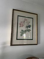 Framed floral wall picture with pink flowers and green leaves, in an ornate dark frame with white matting.