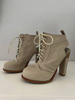 Side view of beige suede high-heeled lace-up shoes with block heel and slight platform, showing shape and materials.