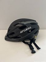 Side angle view of matte black Giro Register MIPS bike helmet showing ventilation slots and adjustable straps