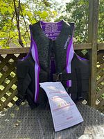 Front view of women's OBrien life jacket size Medium, showing black and purple color with size label and attached tag with instructions.