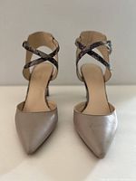 Front view showing pointed beige toe and crisscross snakeskin ankle straps on both shoes.