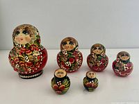 Full set of six Russian nesting dolls arranged in descending size order showing floral hand-painted designs and ladybug decoration on largest doll.