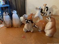 Overview of all porcelain animal figurines showing penguins, raccoons, bear, fox, and other animals