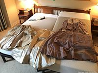 Overview of all four pieces on a mattress: mauve bodice and skirt at right, cream petticoat and lace-trimmed cape at left