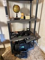 Shelf display showing lot items including camera, camcorder, globe, and accessories