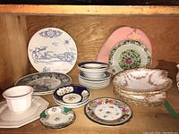 Shelf with 9 Staffordshire stoneware pieces including side plates and bowls, assorted decorative plates including floral and patterned designs.