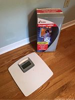Escape ladder box and digital scale on hardwood floor against a blue wall