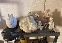 Full lot on black shelf showing assorted figurines including rabbits, lambs, and human figures