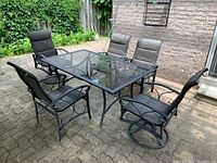Five matching metal-frame mesh chairs around rectangular glass-top table on brick patio, two swivel chairs at near side