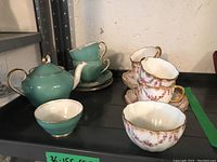 Overview of green Adderley teapot, cups, saucers, sugar bowl and floral Royal Crown Derby cups and saucers