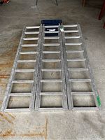 Full view of the fold out aluminum ATV ramp laid out flat on concrete floor
