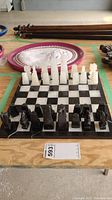 Full view of the onyx chess set with pieces arranged for play on the board. Black and white onyx pieces are polished and carved.