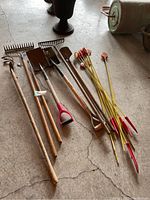 Garden tools and laneway stakes arranged on concrete floor