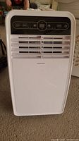 Full front view of white Insignia portable air conditioner unit with horizontal vents and central control panel.