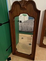 Front view of the Thomasville mirror showing the curved top, vertical groove details in the wood frame, and reflective glass.