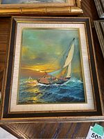 Framed original painting showing a sailboat on the choppy sea during sunset with warm and cool tones, signed by the artist 'Dani'.