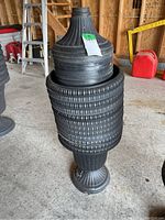 Photo of stacked black plastic plant pots and stands with visible textured ribbing and grooved design.