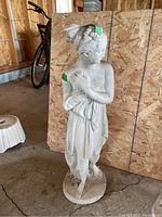 Front angle of the white concrete statue showing detailed draped clothing and facial features.