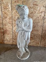 Front and side view of the concrete statue showing draped garment and classical hair style.