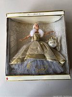 Front view of Special 2000 Edition Celebration Barbie doll in original box. Doll wears gold and silver gown with white fur stole and holds 2000 ornament accessory.