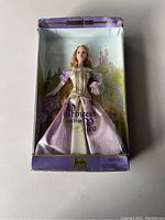 Photo of the Princess and the Pea Barbie doll in original box showing doll in purple gown and box background with castle illustration