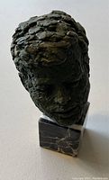 Miniature bust sculpture of JFK's head with textured surface in dark finish and marble base.