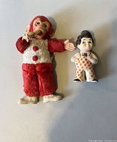Photo of a Big Boy doll bank and a vintage red and white monkey plush doll on a flat surface