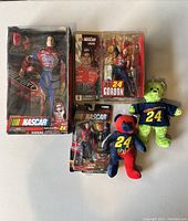Five Jeff Gordon NASCAR collectibles in the image: three boxed action figures and two plush bears, all unopened with some box wear visible.