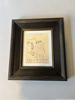 Front view of framed print showing three stylized figures in dark wood frame