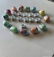 Photo of 10 mini Simpsons mugs, 1 Itchy & Scratchy mug, and 13 unopened Simpsons bobblehead figures in colorful capsules arranged on a flat surface.