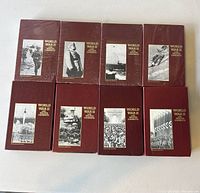 Top view of 8 World War II documentary Beta tapes with Walter Cronkite, arranged in 2 rows of 4. Covers are dark red with historic black and white photos and titles.