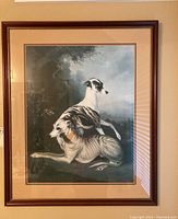 Full view of framed artwork showing two dogs, one resting and one sitting on top, with naturalistic background.