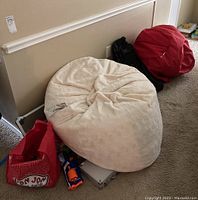 Photo showing cream bean bag, red bean bag, blue Nerf gun, red shopping bag, two black backpacks.