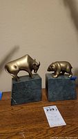 Front view of brass bison and bear bookends on marble bases