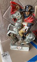 Napoleon riding a horse decanter figurine, showing half profile with detailed paint and red cape.