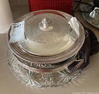 Silver plated serving dish with lid placed on silver plated tray, glass plate underneath