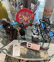 View of the whole lot on a glass table showing all figurines, plate on stand, napkin holder, and fish card holder with a business card.