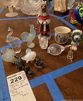 Photo showing glass animal figurines, metal rabbit, Goebel ceramic figurine, and small metal miniatures on wooden surface.