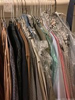 Photo of men's shirts on hangers, including corduroy, plaid, and solid colors, some dry cleaned and wrapped in plastic