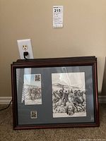 Stack of four framed black and white Civil War commemorative prints against a wall near an outlet, with visible reflections on glass.