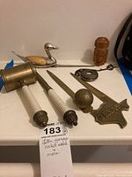 Overview of entire lot arranged on white surface showing all items including letter openers, pocket watch, gavel, wood figure, and duck figurine.