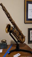 Saxophone displayed on black adjustable stand on wooden table.
